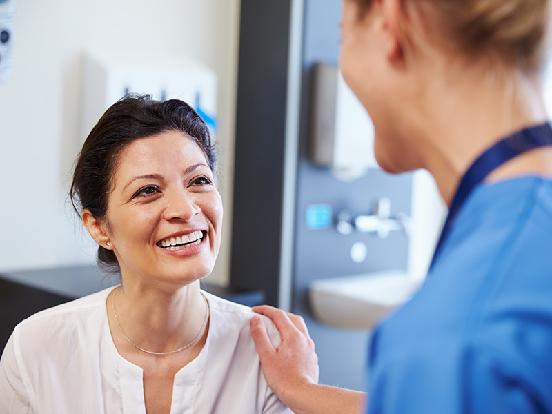 Female doctor with hand on female patient's shoulder